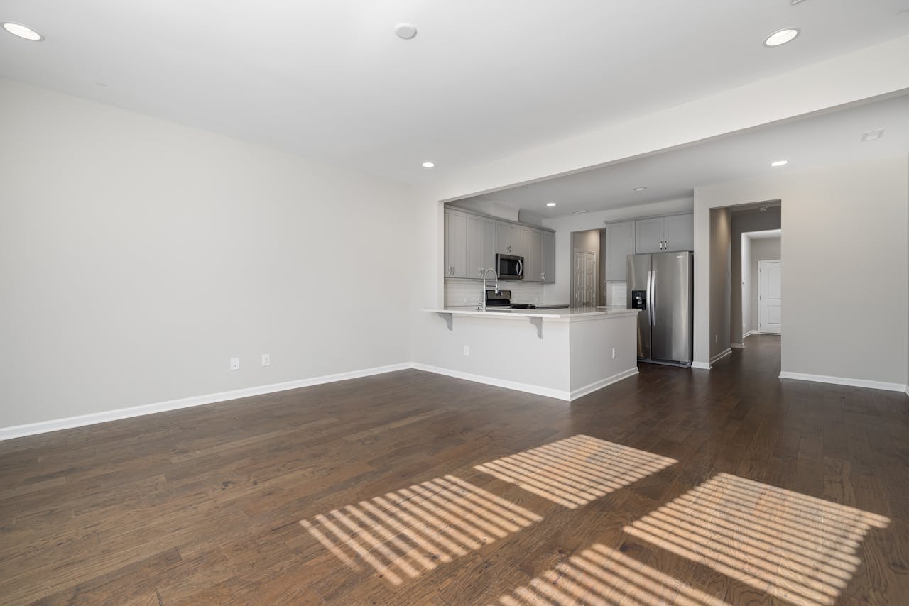 Spacious empty apartment featuring modern kitchen and hardwood floors.
