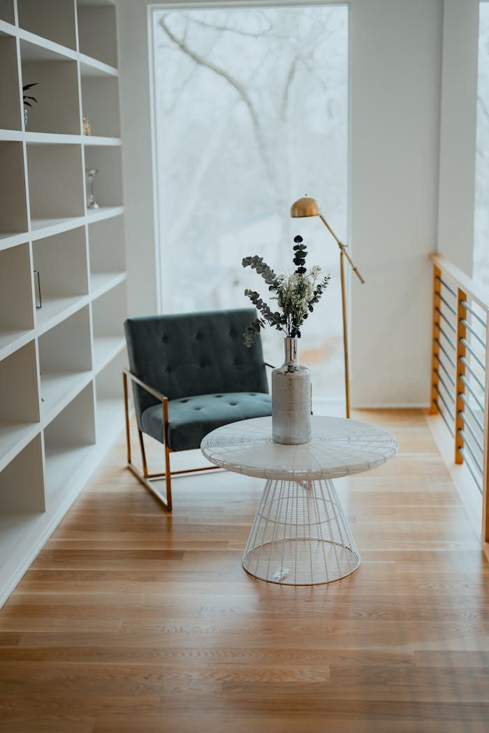 Elegant interior featuring an armchair and centerpiece table with a plant, framed by a large window.